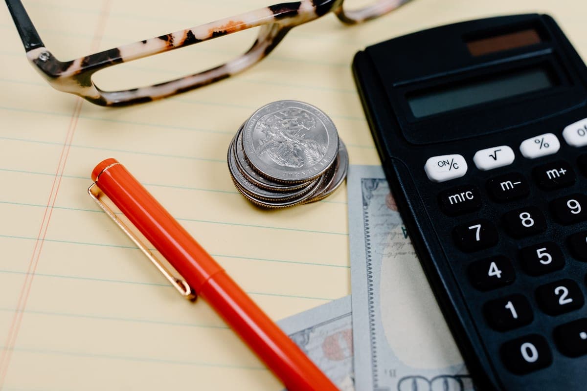 A calculator, coins and glasses on a notepad