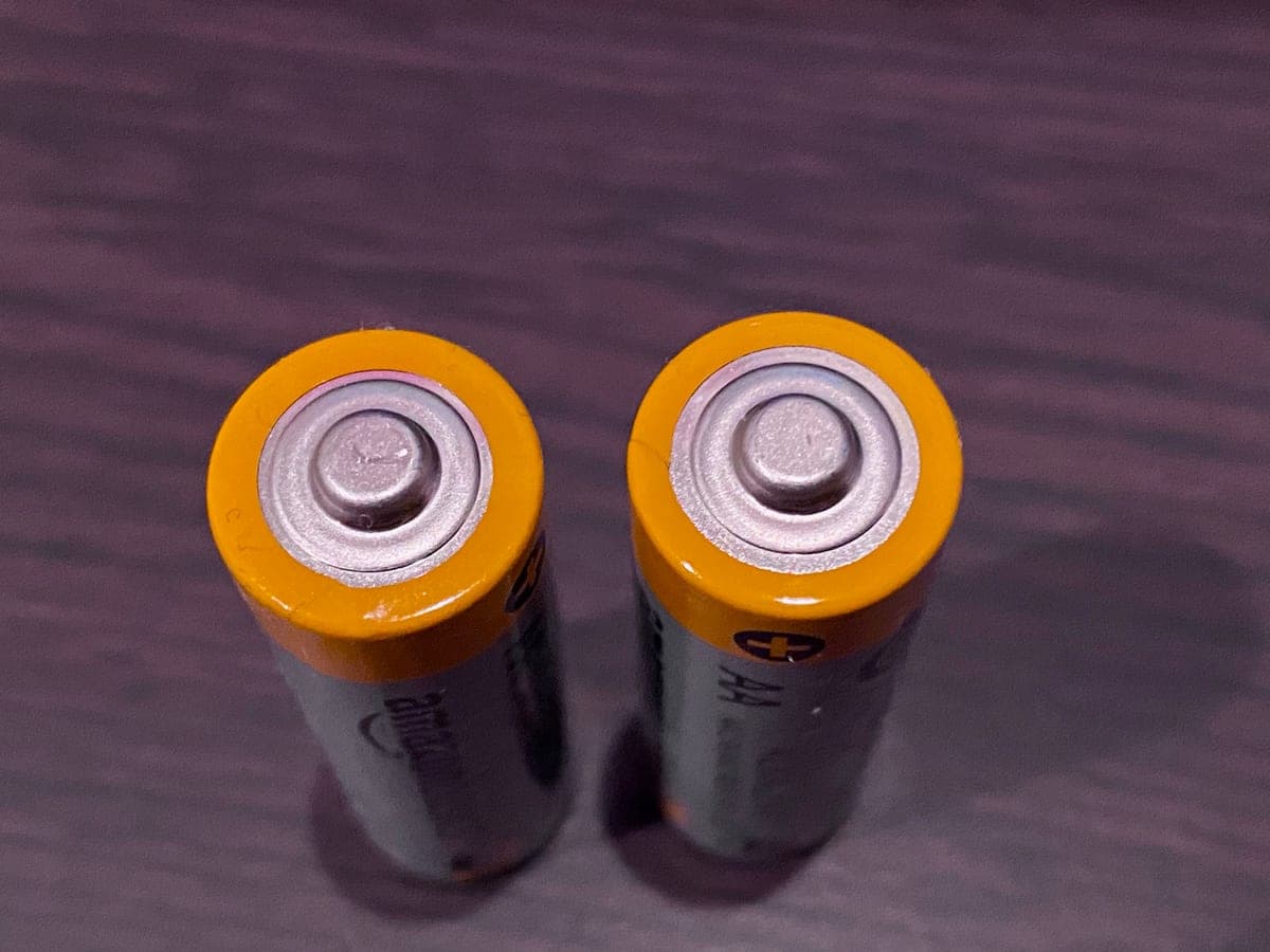 Two AA batteries on a dark surface